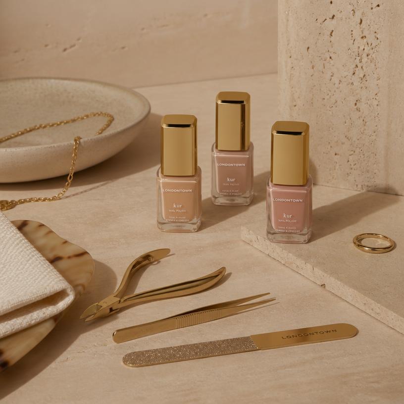 Nail polish bottles and manicure tools on a beige stone surface